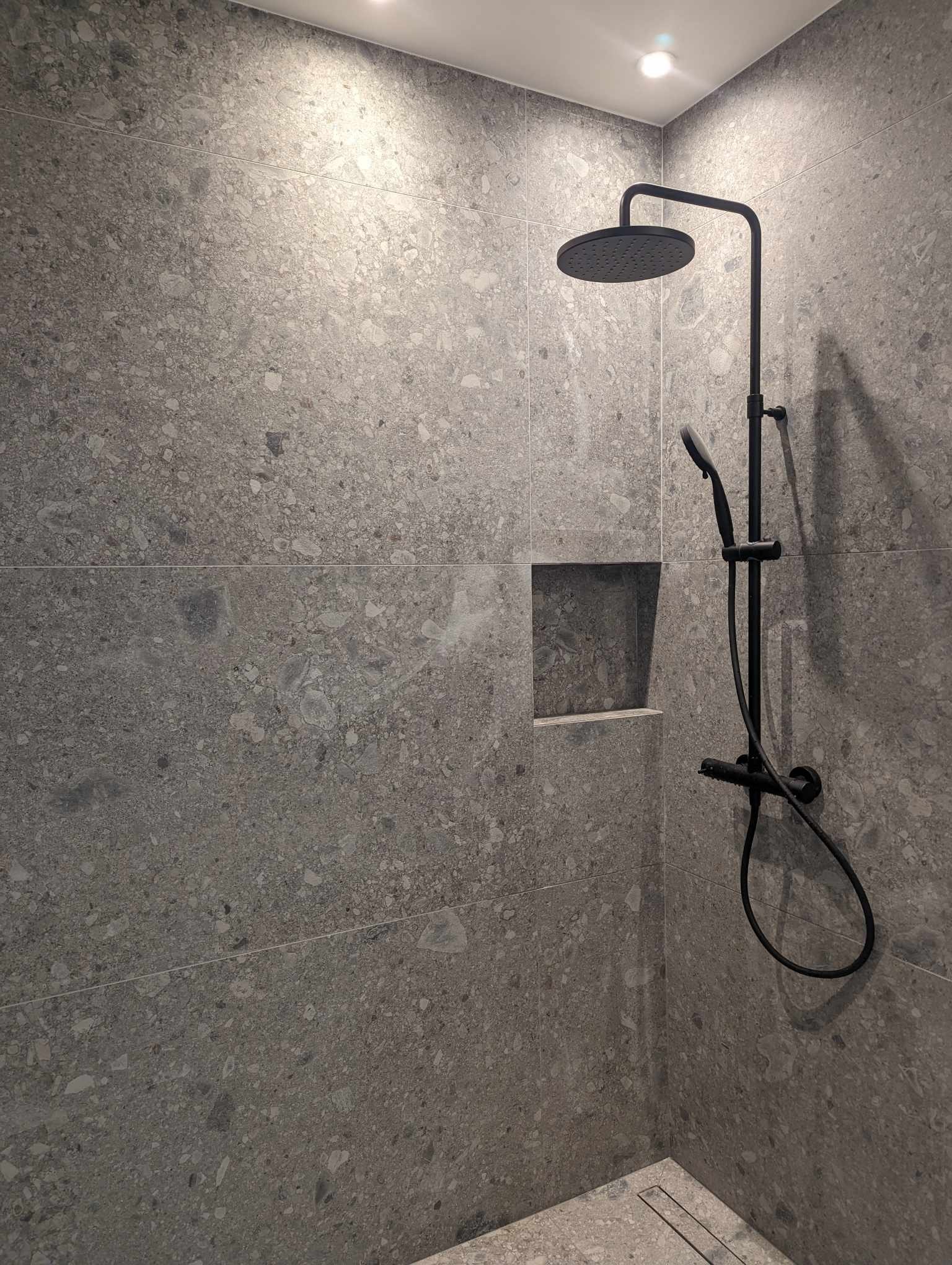 Completed shower with stone-effect tiles and black fittings