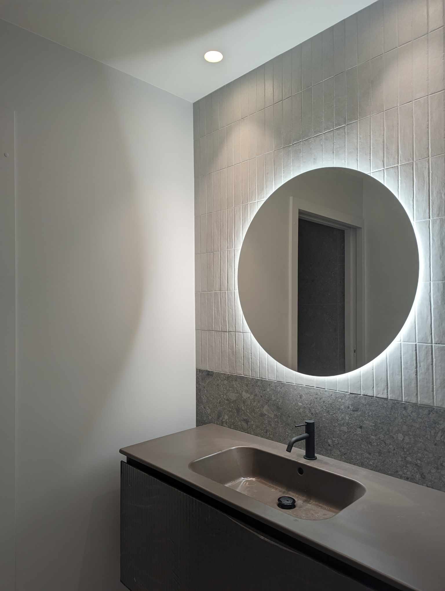 Completed bathroom vanity with round illuminated mirror